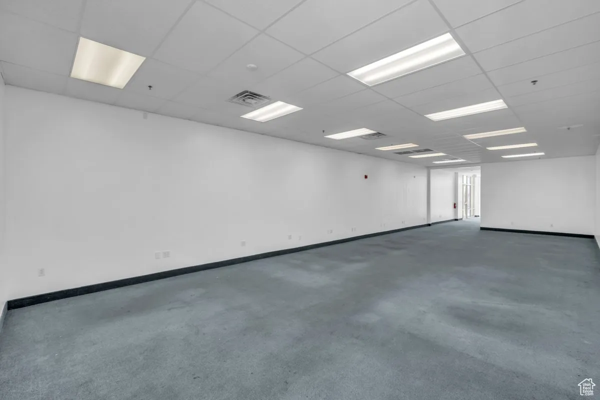 Spare room featuring carpet flooring, a drop ceiling, and fire sprinkler in ceiling