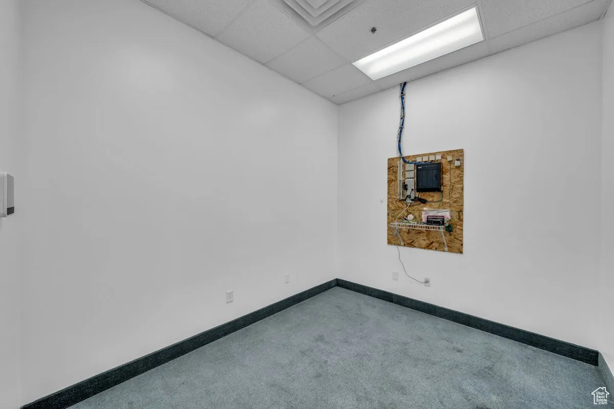 Carpeted empty room with a paneled ceiling and baseboards