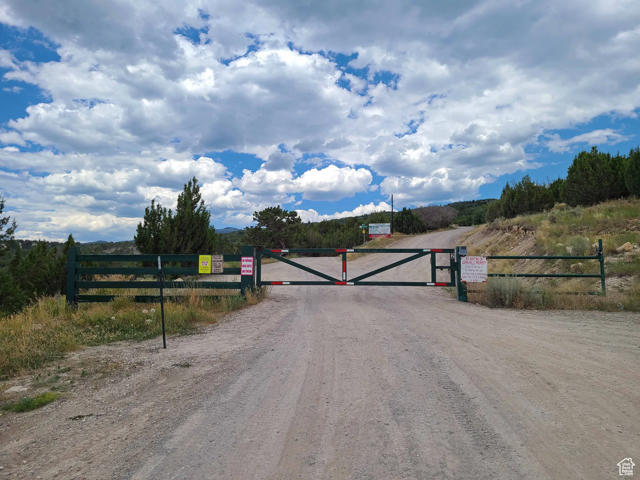 View of dirt / gravel road with a gate and a view of countryside