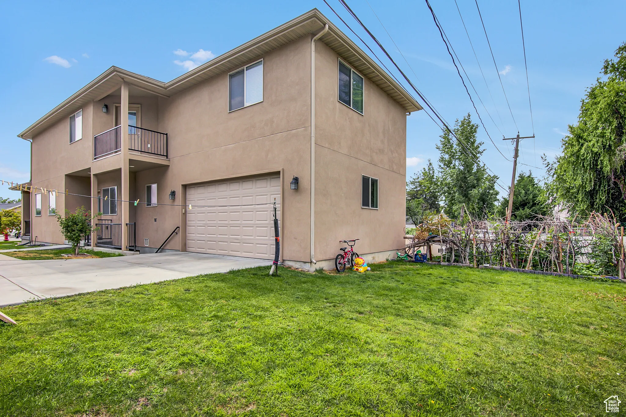 View of side of home with an attached garage, stucco siding, concrete driveway, and a yard