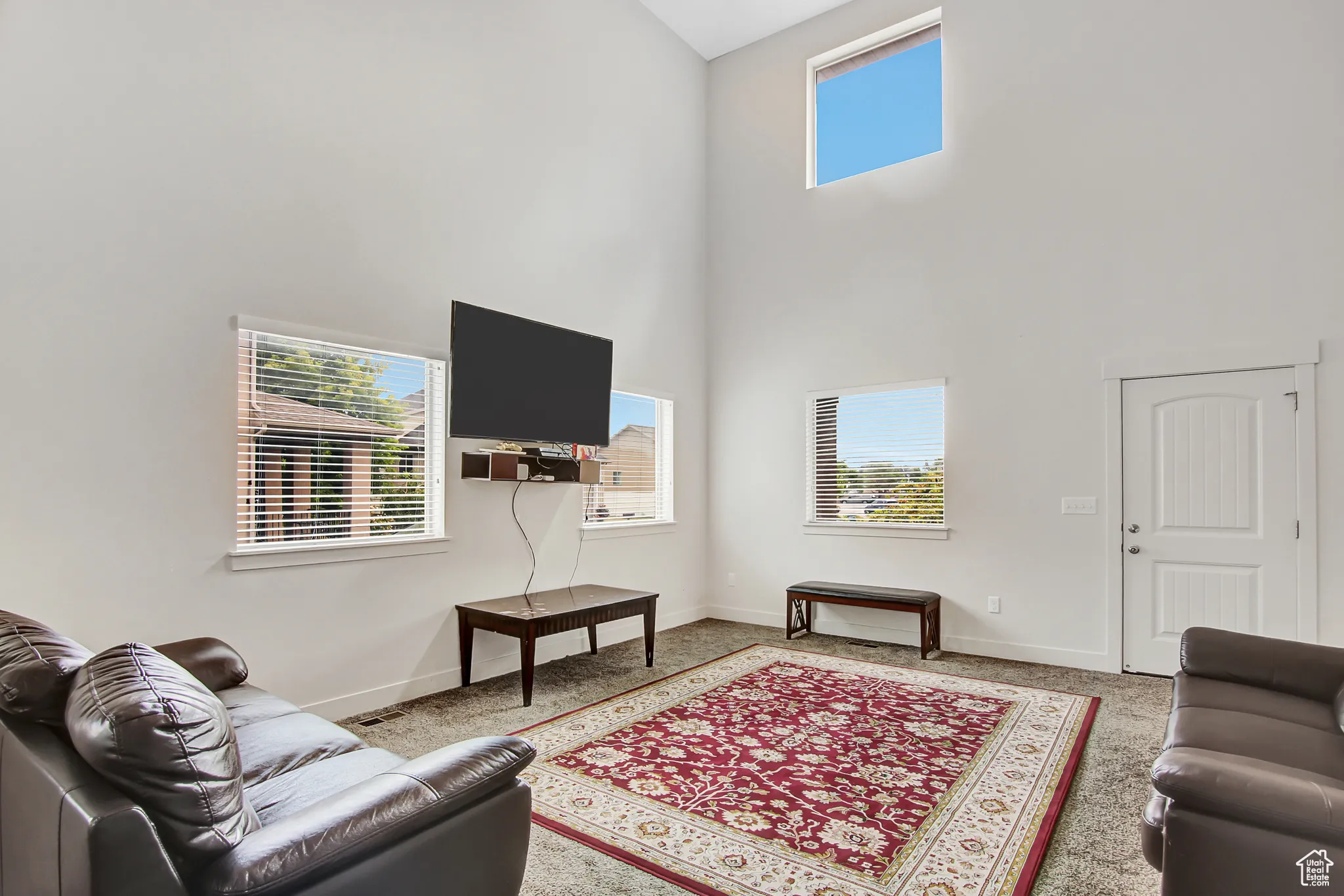 Carpeted living area featuring a high ceiling and baseboards