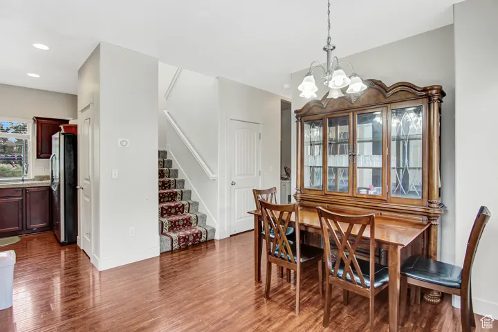 Dining space featuring a chandelier, dark wood-type flooring, stairs, and recessed lighting