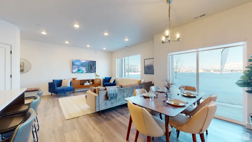 Dining space with light wood-type flooring, recessed lighting, and a chandelier