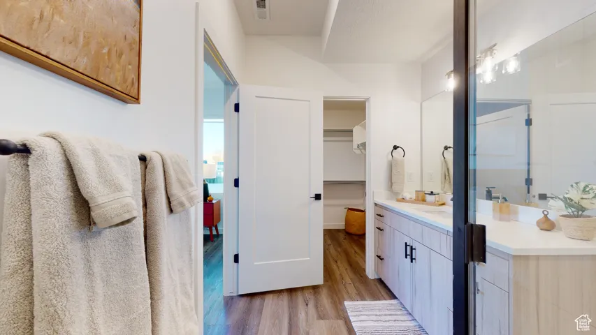 Full bath with wood finished floors, vanity, and a walk in closet