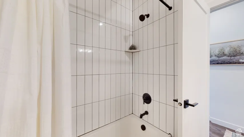 Bathroom featuring shower / bath combo and wood finished floors