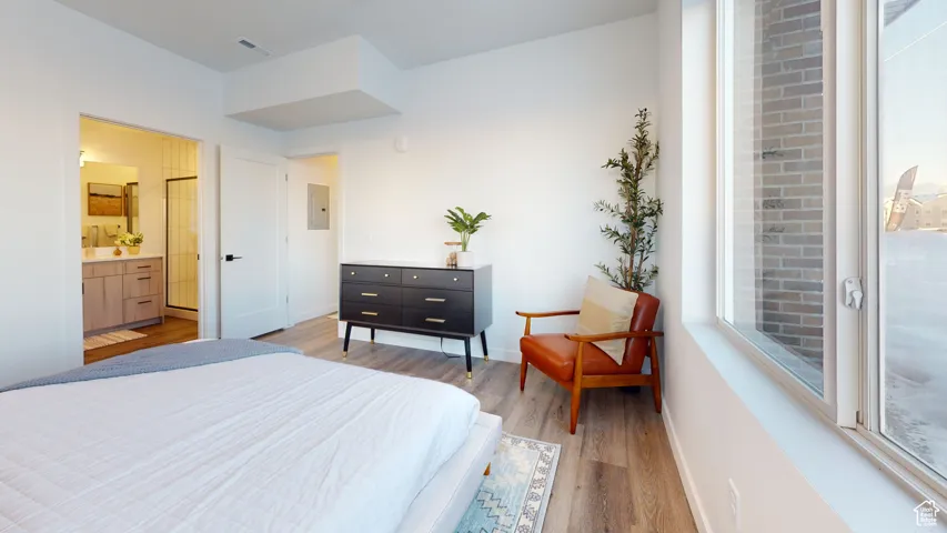 Bedroom with light wood-style flooring, electric panel, and multiple windows