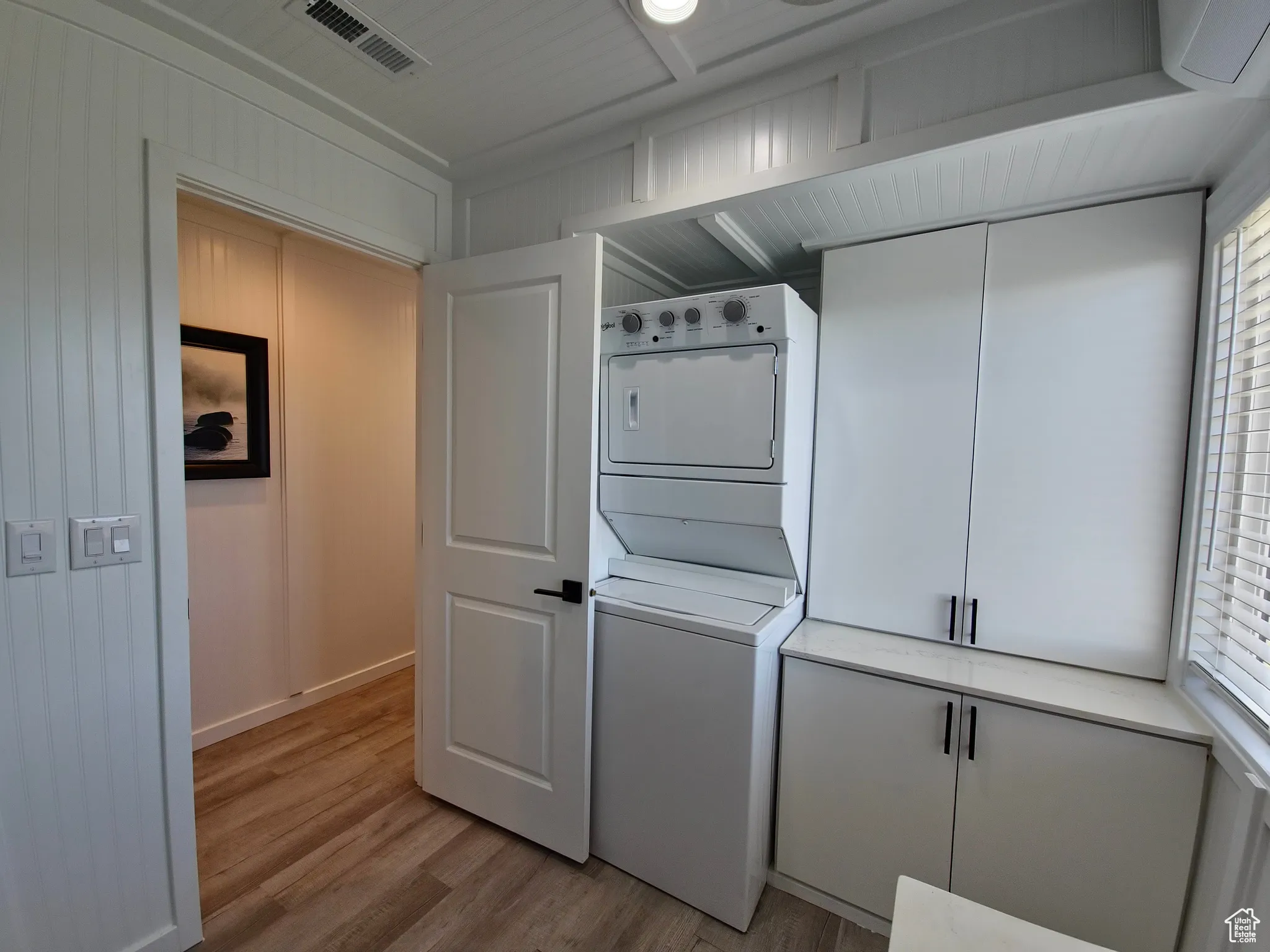 Washroom featuring stacked washing machine and dryer and light wood-style floors
