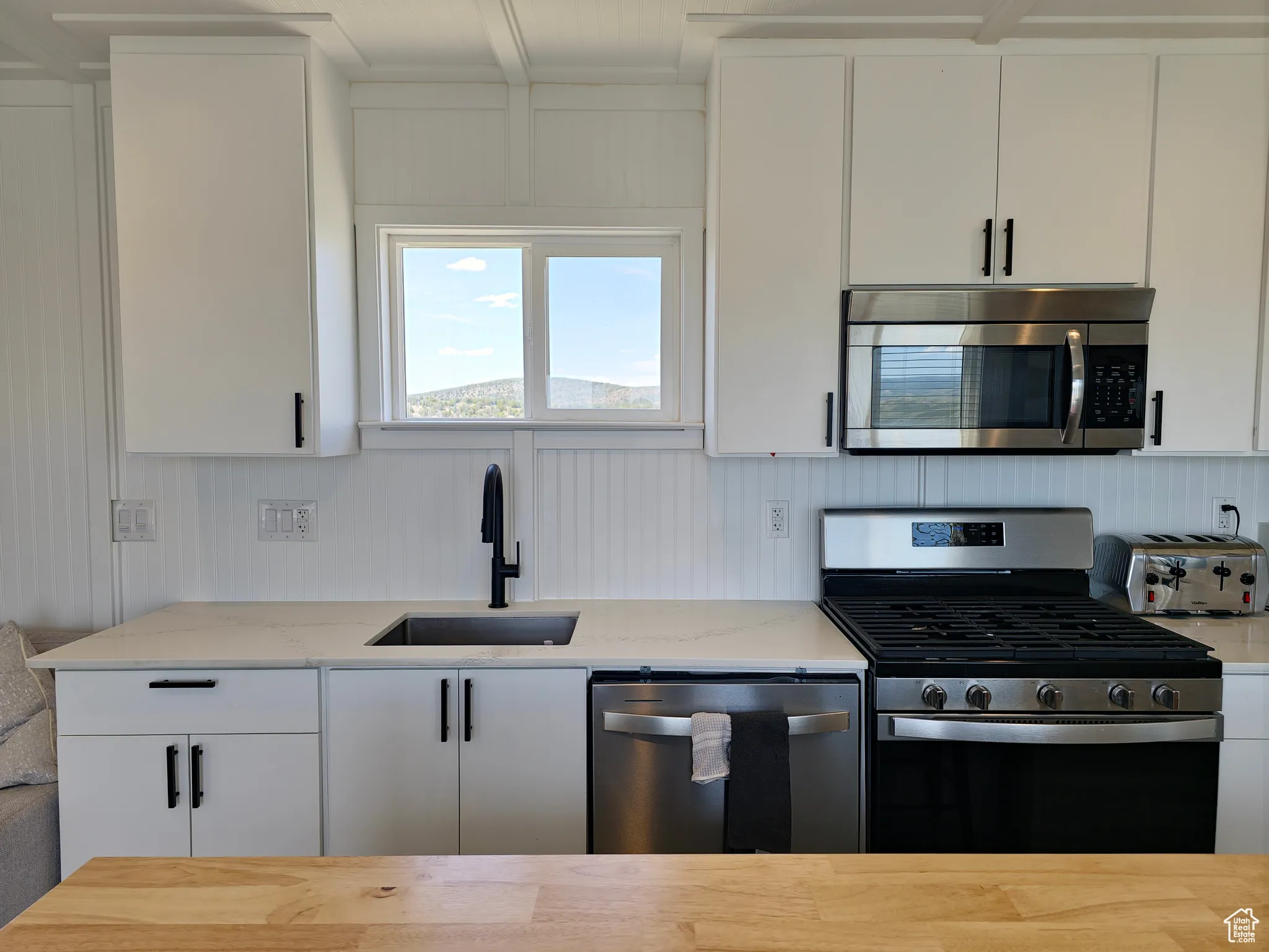 Kitchen featuring appliances with stainless steel finishes, light stone countertops, and white cabinets