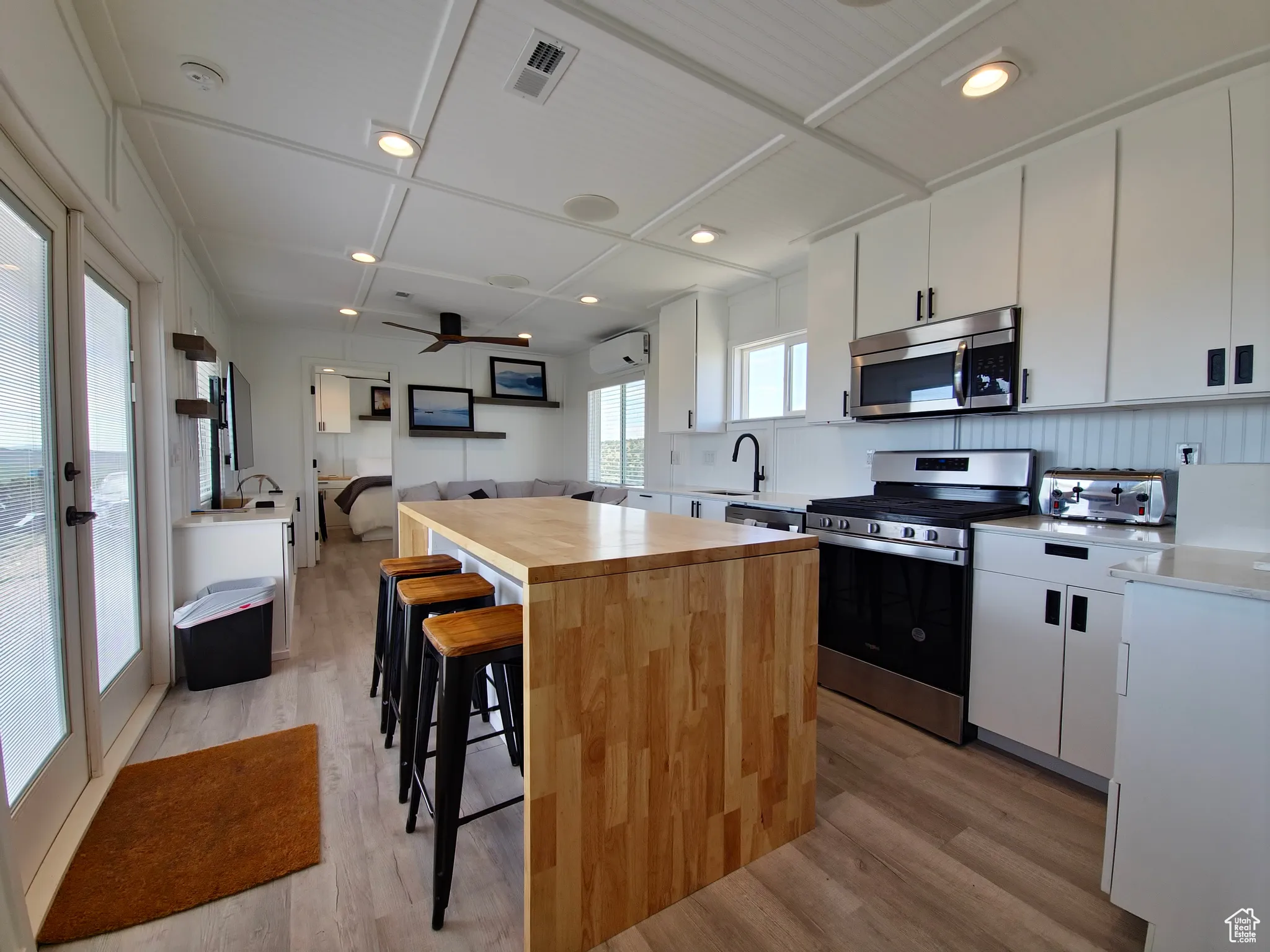Kitchen with stainless steel appliances, light wood finished floors, a kitchen island, wooden counters, and a breakfast bar
