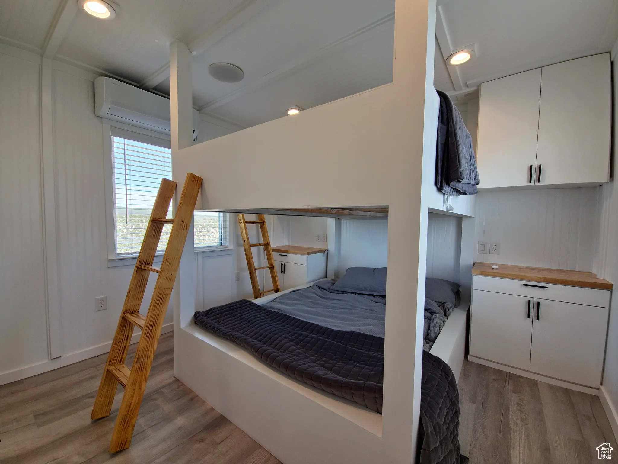 Bedroom with light wood-style flooring and a wall unit AC