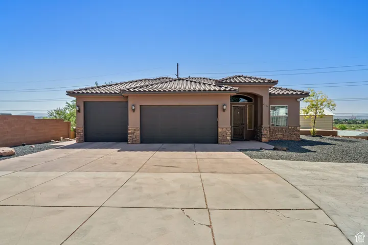 Mediterranean / spanish-style house featuring stone siding, stucco siding, a garage, concrete driveway, and a tile roof
