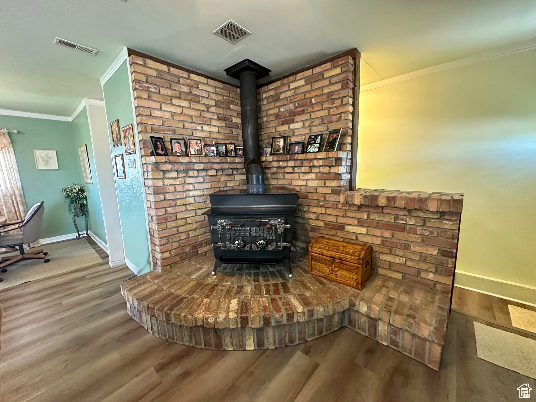 Detailed view of crown molding, wood finished floors, and a wood stove