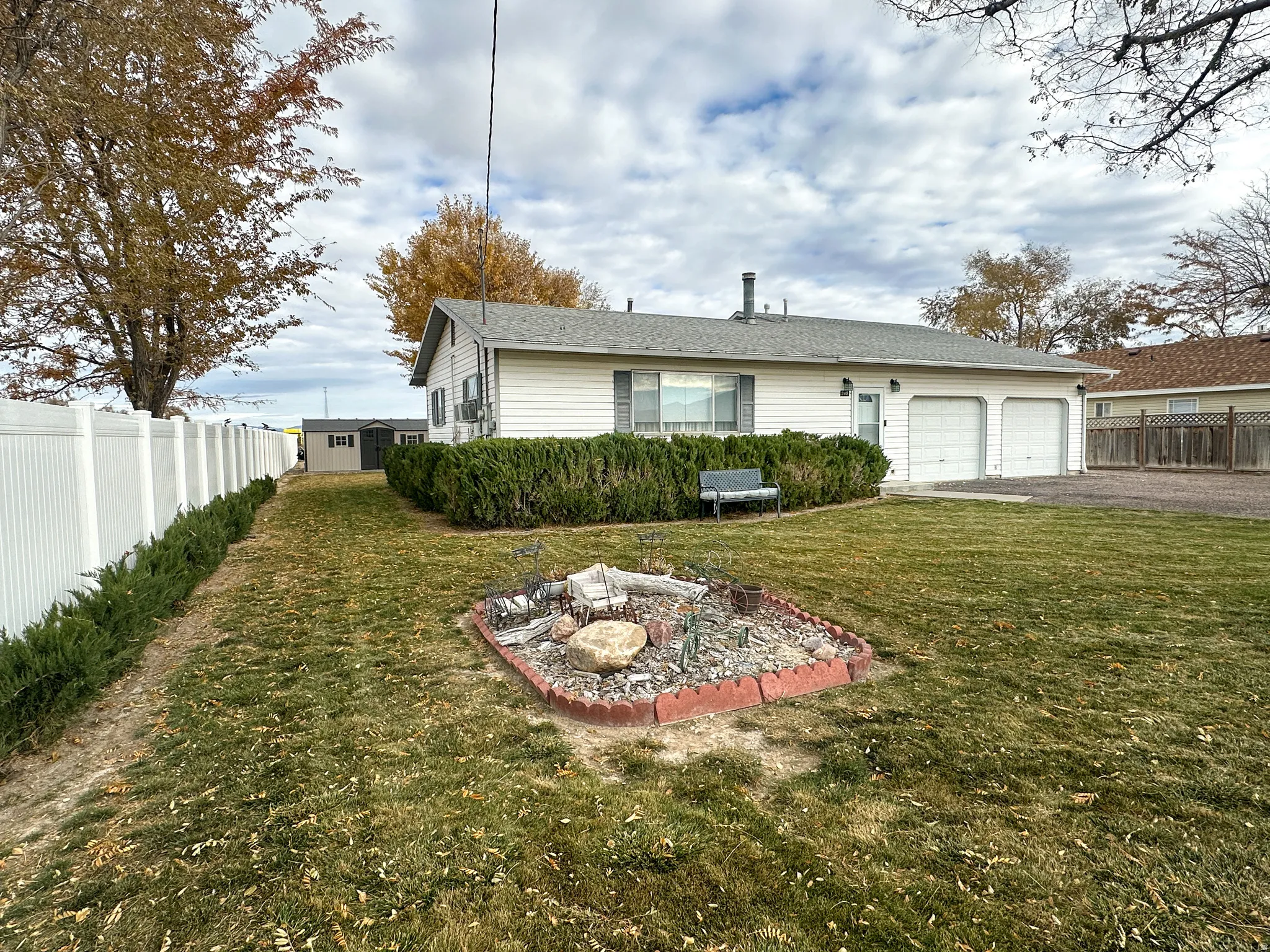 Back of house featuring asphalt driveway, a fire pit, an attached garage, and roof with shingles