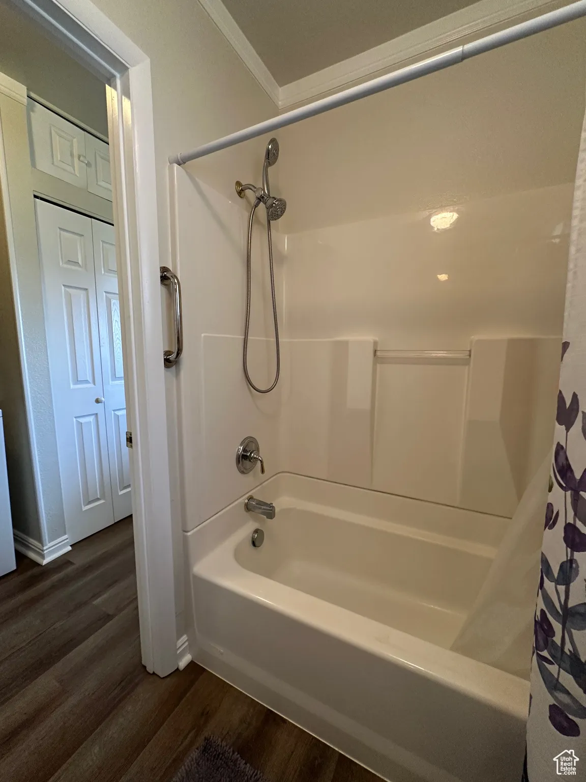 Full bath featuring wood finished floors, shower / bath combo with shower curtain, and crown molding