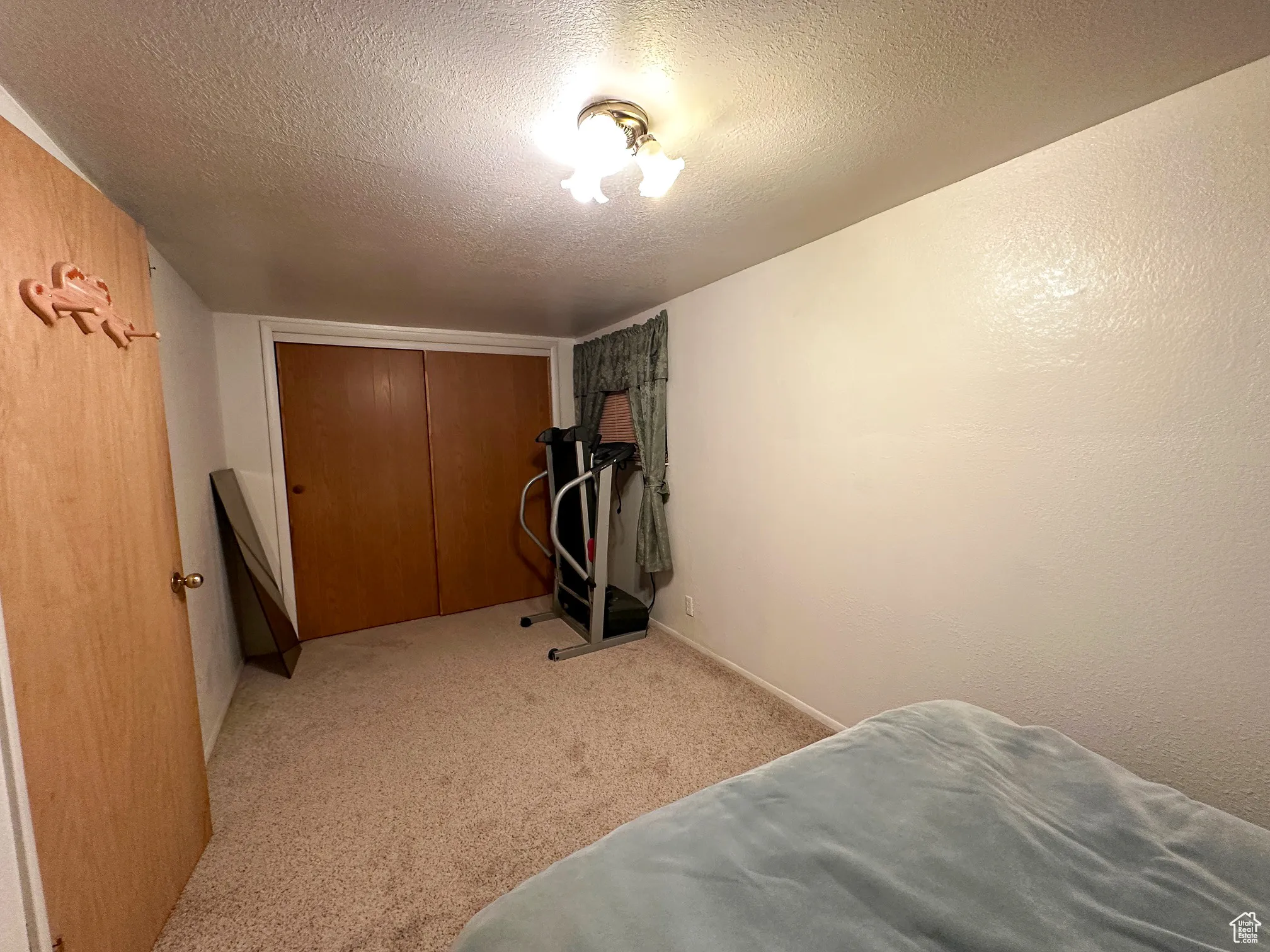 Bedroom featuring a textured ceiling, light carpet, and a closet