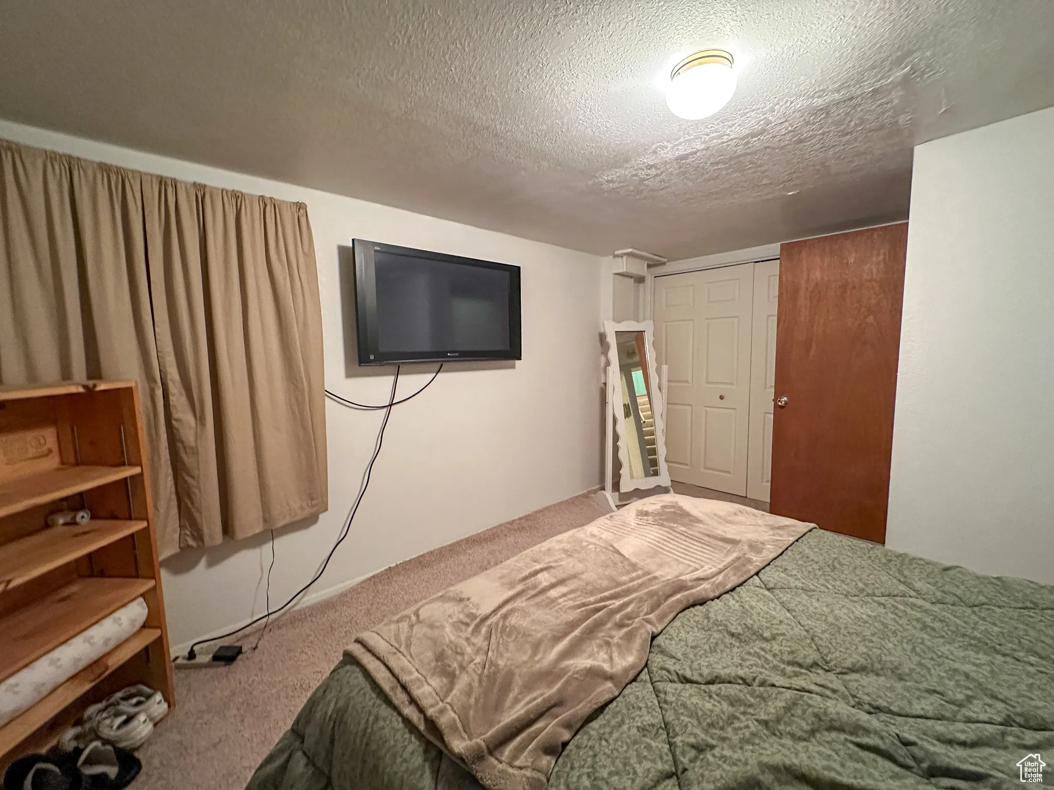 Bedroom featuring carpet, a textured ceiling, and a closet