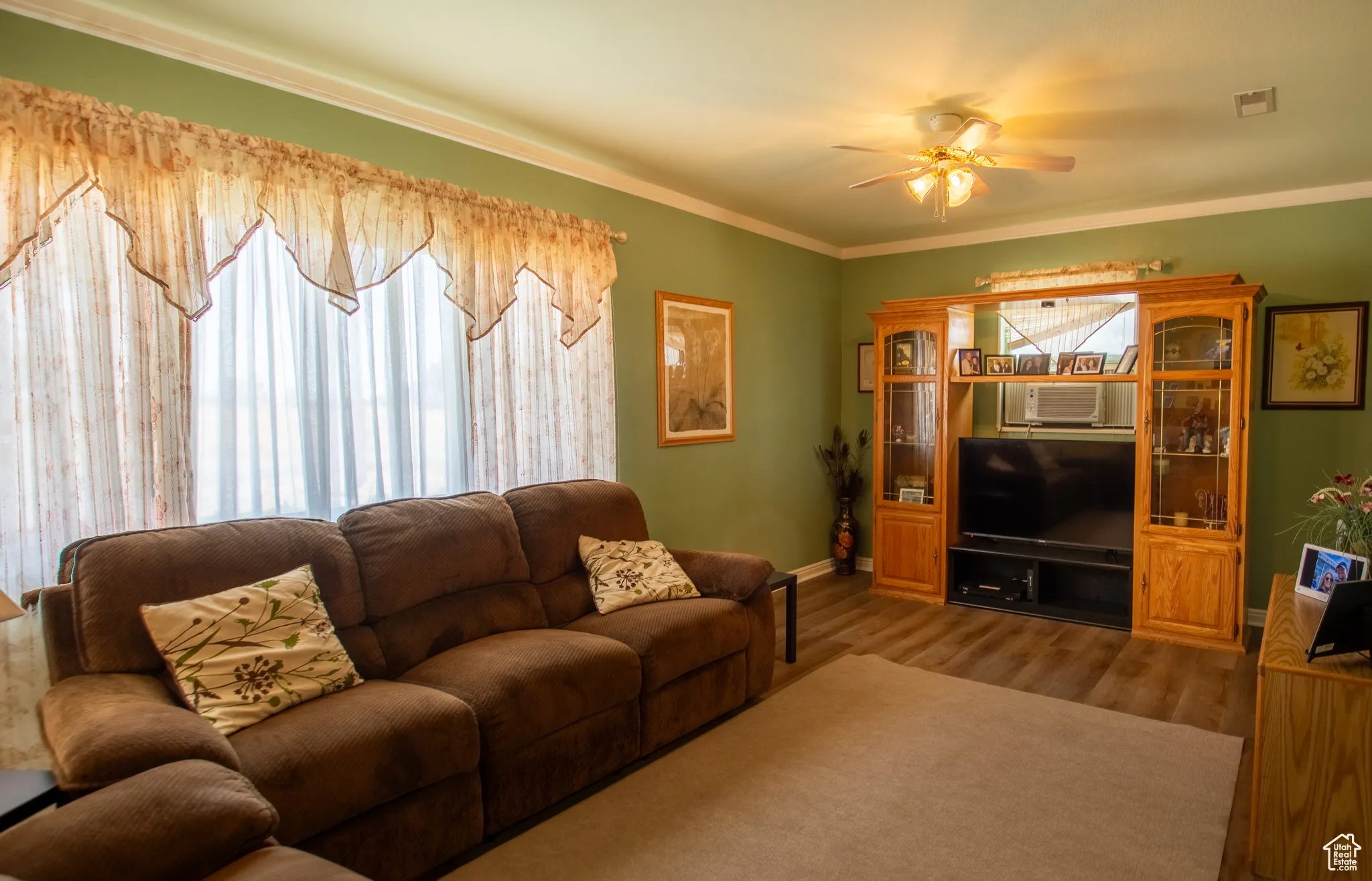 Living room featuring ceiling fan, wood finished floors, and ornamental molding