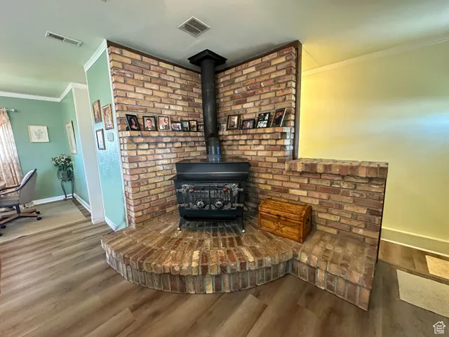 Detailed view of crown molding, wood finished floors, and a wood stove