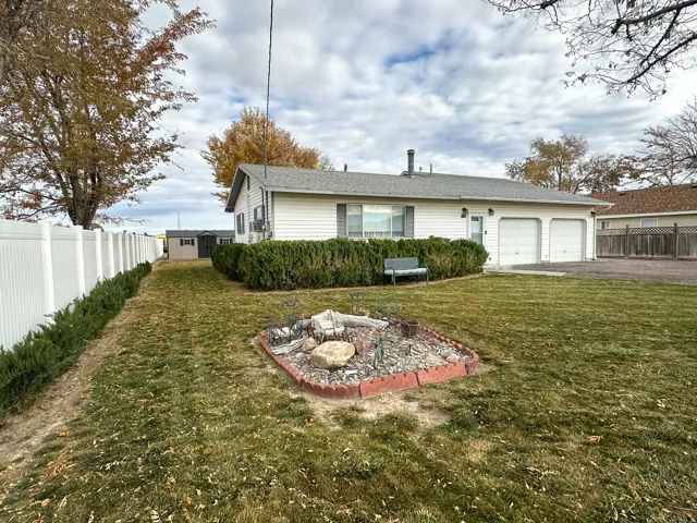 Back of house featuring asphalt driveway, a fire pit, an attached garage, and roof with shingles