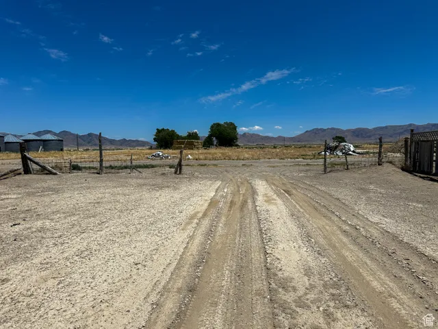 View of dirt / gravel road featuring a view of countryside and a mountain view