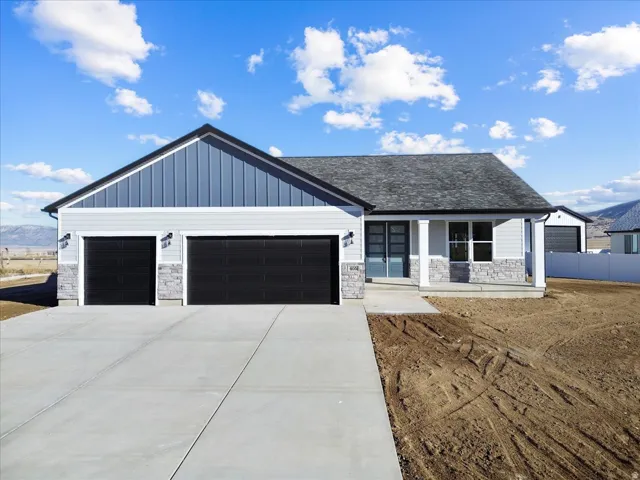 View of front facade featuring covered porch, stone siding, board and batten siding, and a garage