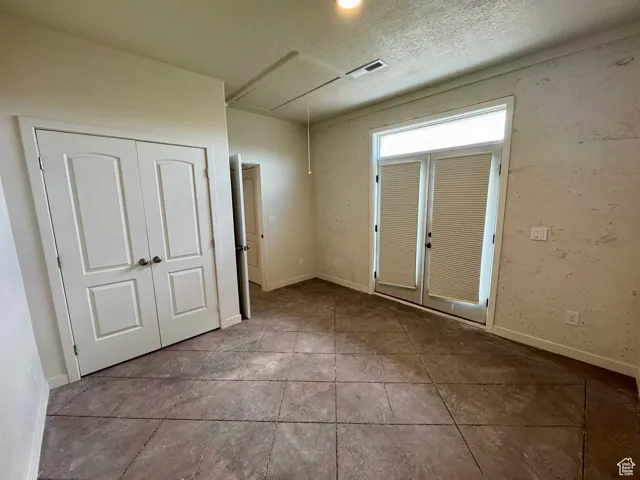 Tiled spare room featuring attic access and a textured ceiling