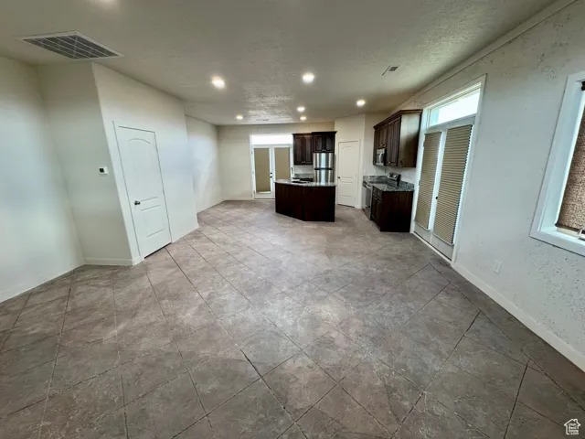 Unfurnished living room featuring recessed lighting, healthy amount of natural light, and a textured ceiling