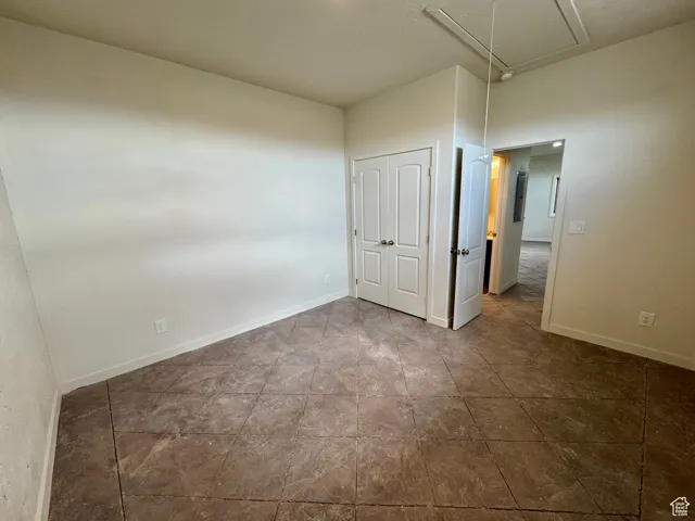 Unfurnished bedroom with attic access and a closet