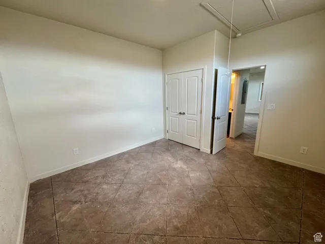 Unfurnished bedroom featuring attic access and a closet
