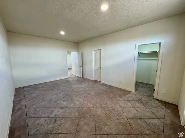 Unfurnished bedroom with a textured ceiling, a spacious closet, and recessed lighting