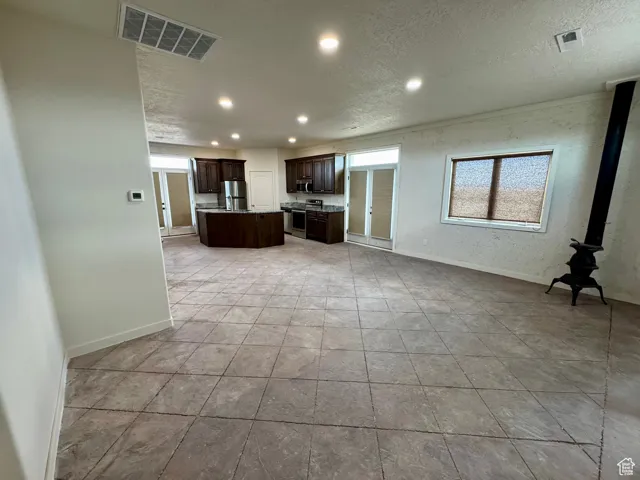Unfurnished living room featuring recessed lighting, a textured ceiling, and a wood stove