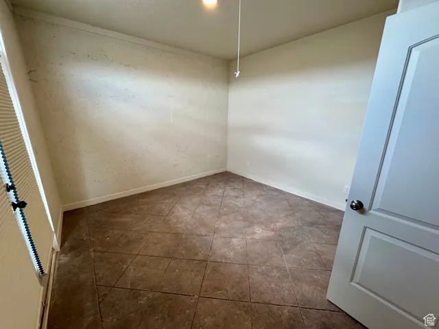 Spare room with baseboards and dark tile patterned floors