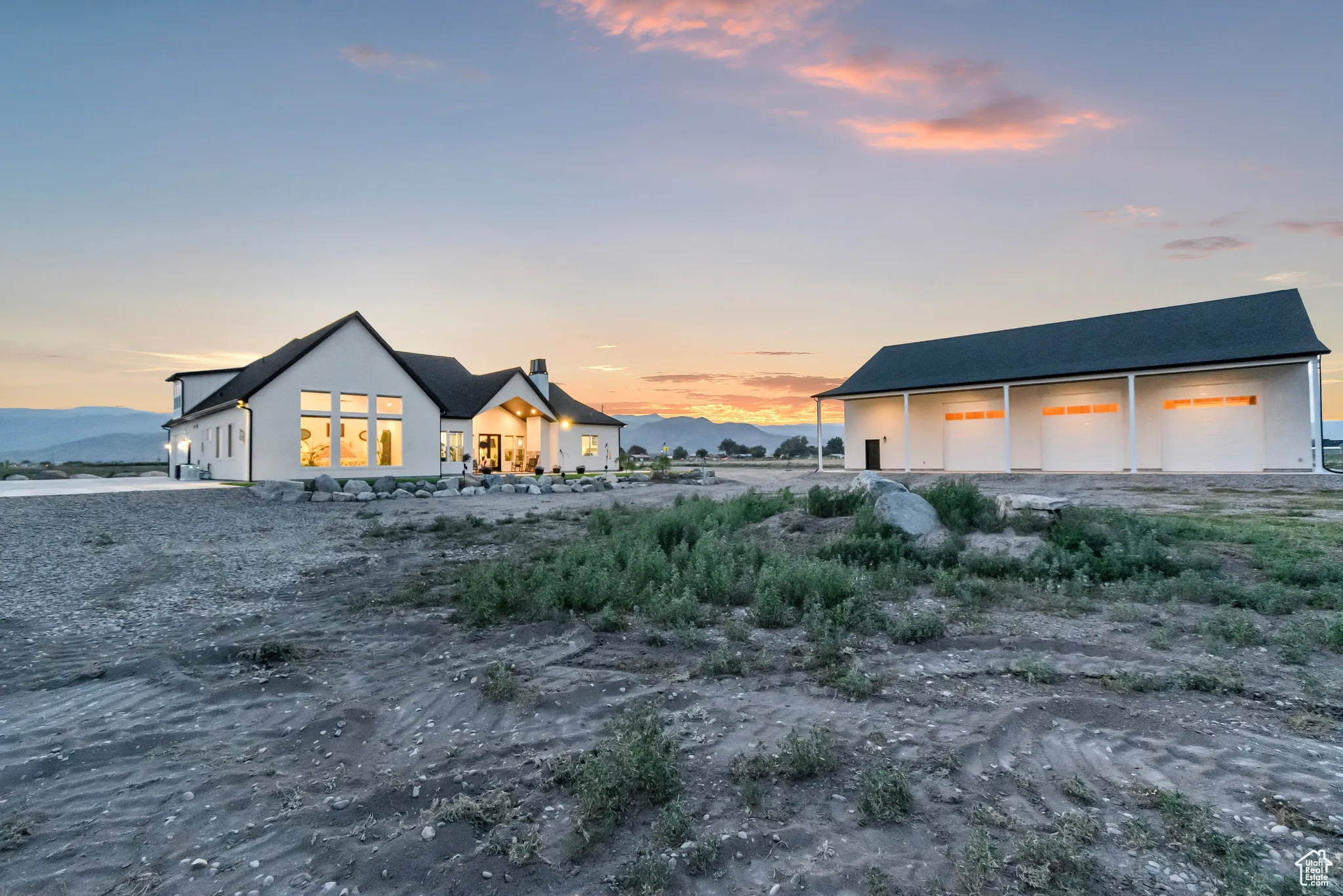 Back of house with a garage, an outbuilding, and stucco siding