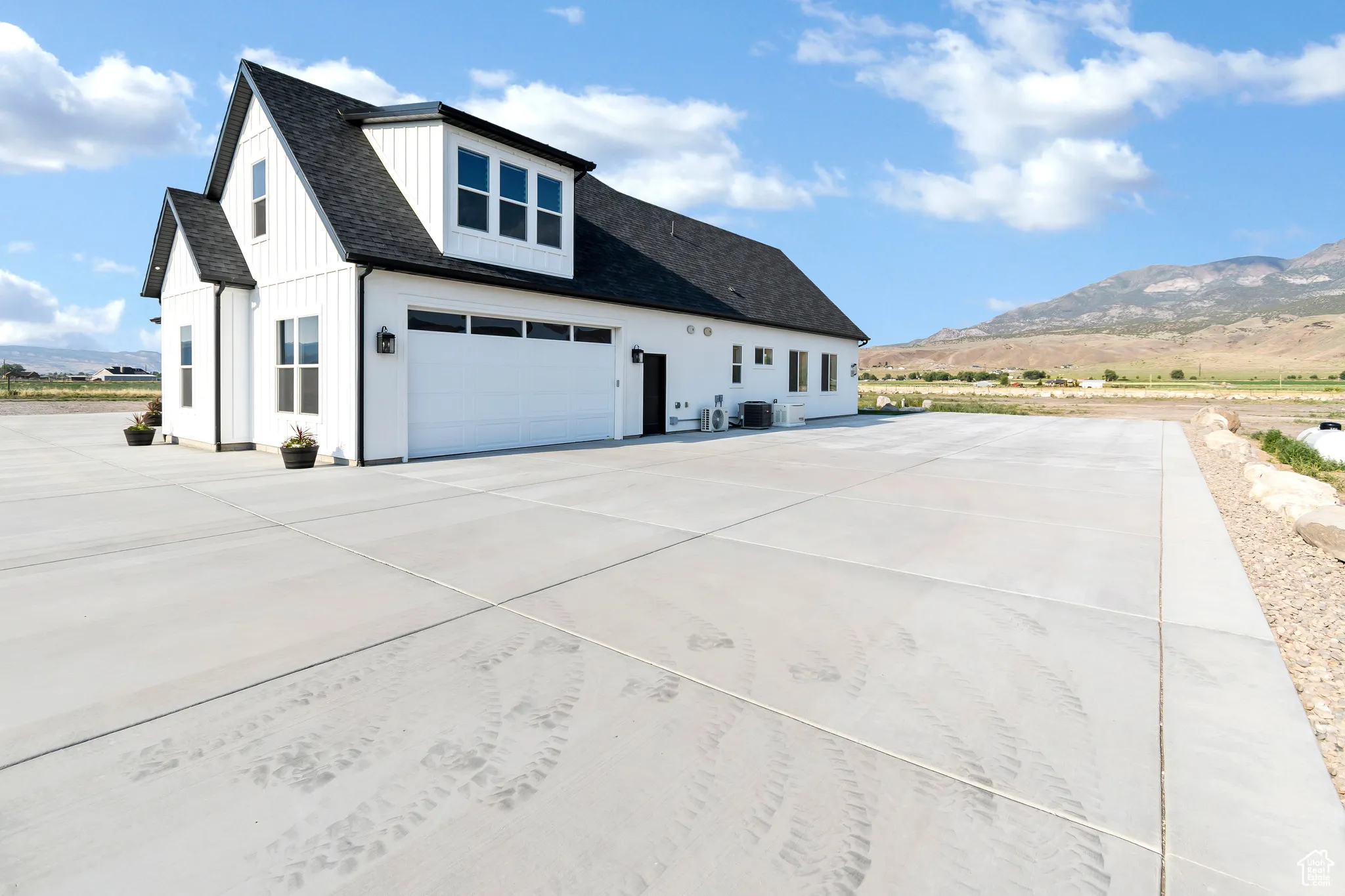 View of side of property featuring a mountain view, concrete driveway, a garage, board and batten siding, and roof with shingles