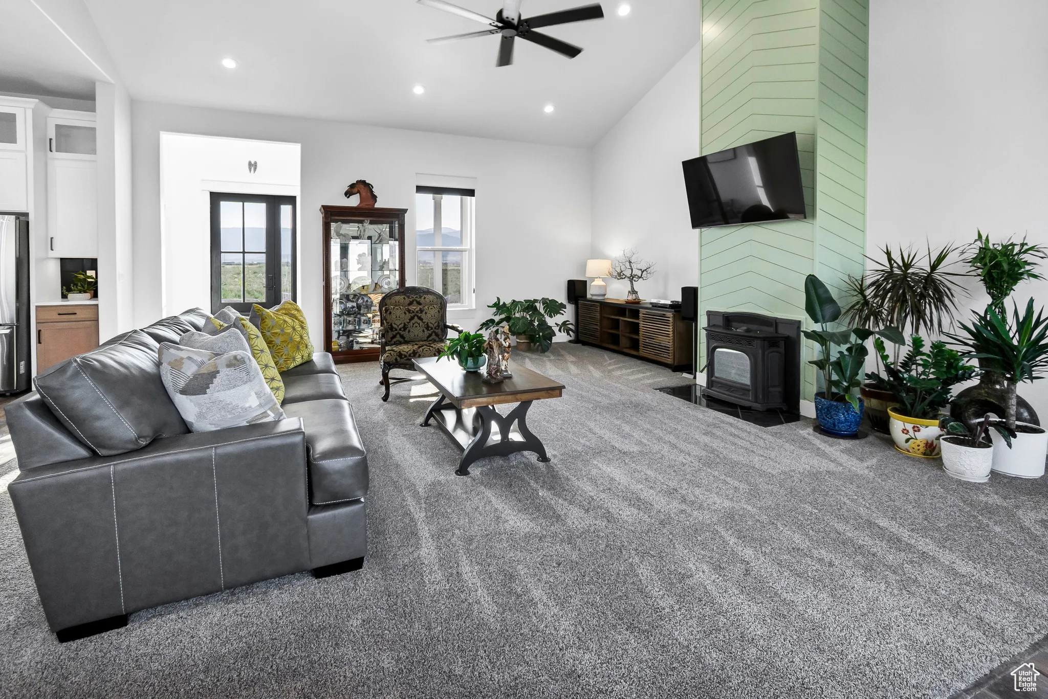 Living room with a wood stove, a ceiling fan, recessed lighting, carpet flooring, and lofted ceiling