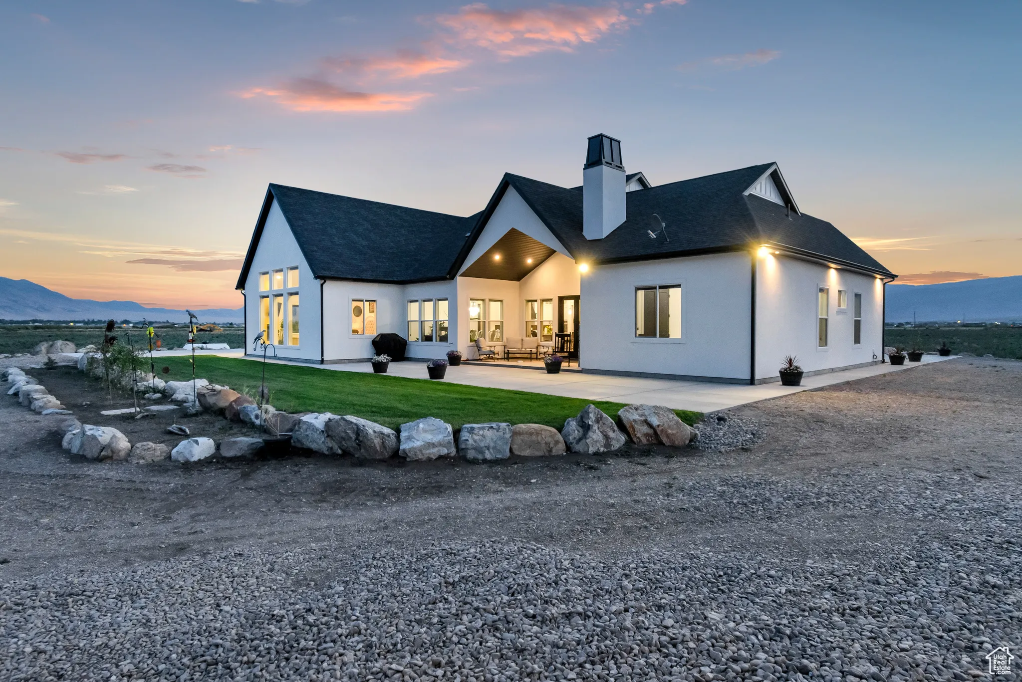 Back of property featuring a chimney, a patio area, a shingled roof, a lawn, and a mountain view