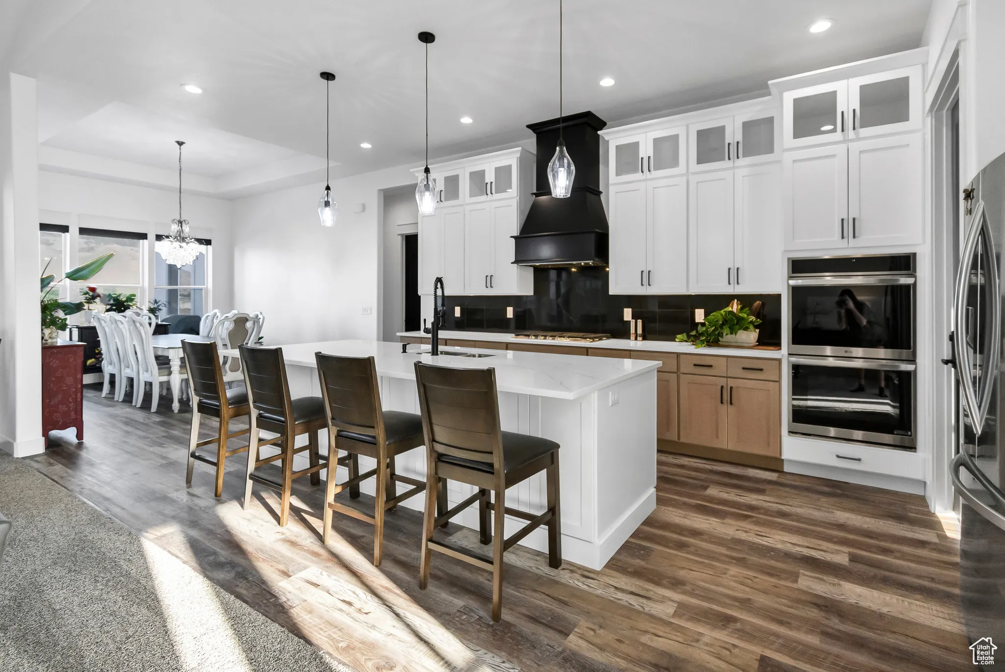 Kitchen featuring appliances with stainless steel finishes, light countertops, decorative backsplash, a chandelier, and dark wood-style floors