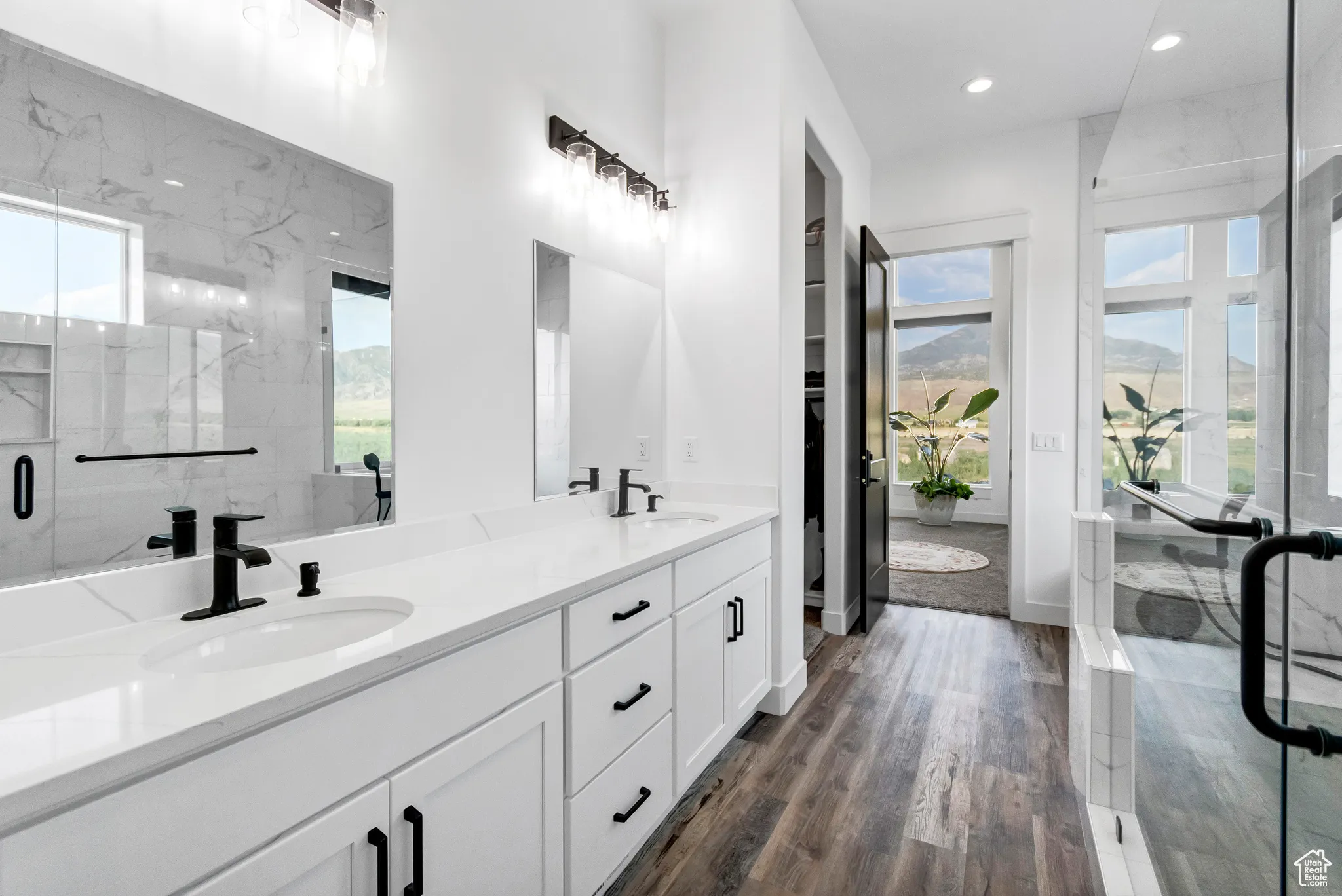 Bathroom with plenty of natural light, double vanity, recessed lighting, a marble finish shower, and wood finished floors