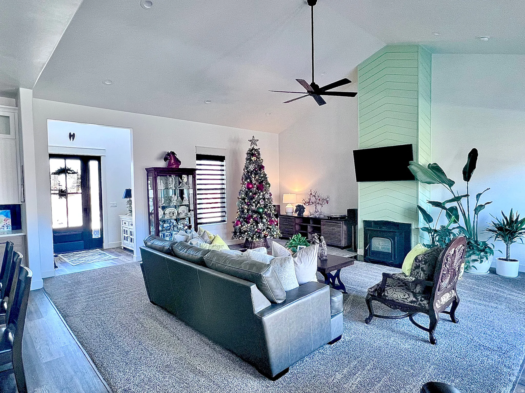 Living area featuring high vaulted ceiling, a large fireplace, and a ceiling fan
