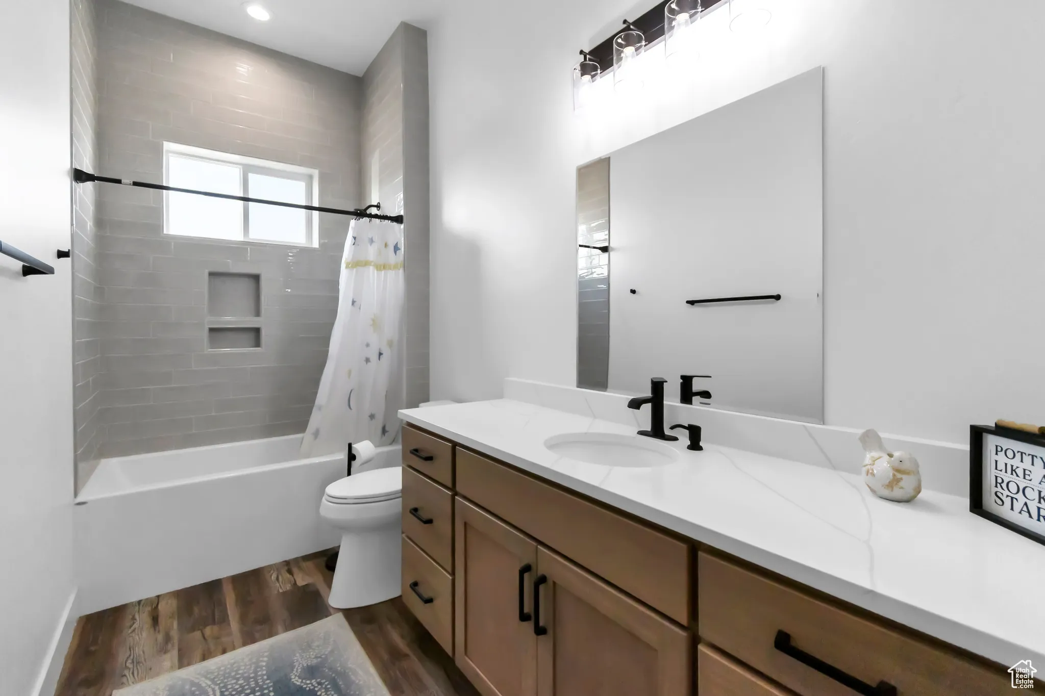 Bathroom featuring vanity, wood finished floors, and shower / tub combo with curtain