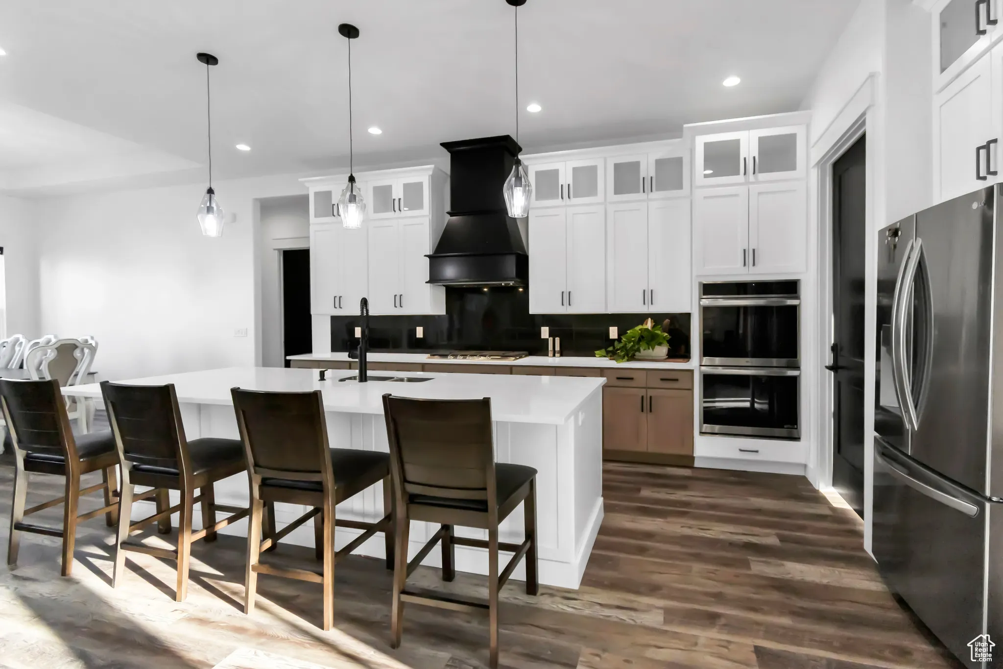 Kitchen featuring appliances with stainless steel finishes, decorative backsplash, light countertops, dark wood-type flooring, and a kitchen breakfast bar