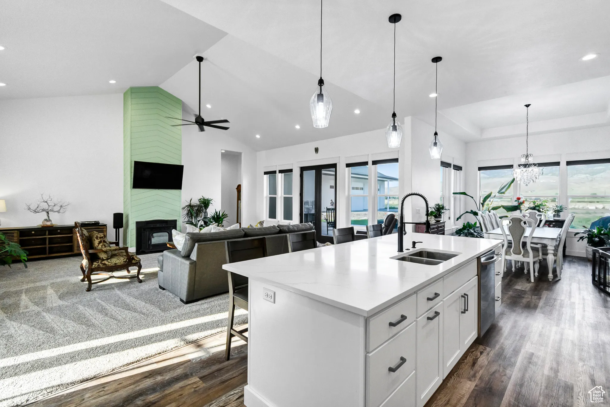 Kitchen with dark wood finished floors, stainless steel dishwasher, a kitchen island with sink, white cabinets, and recessed lighting