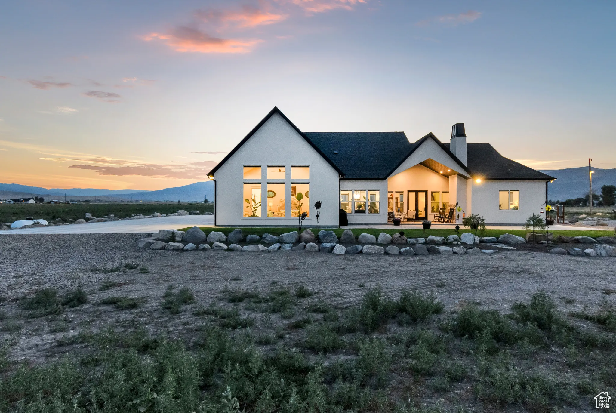 Back of house at dusk with stucco siding, a chimney, and a mountain view