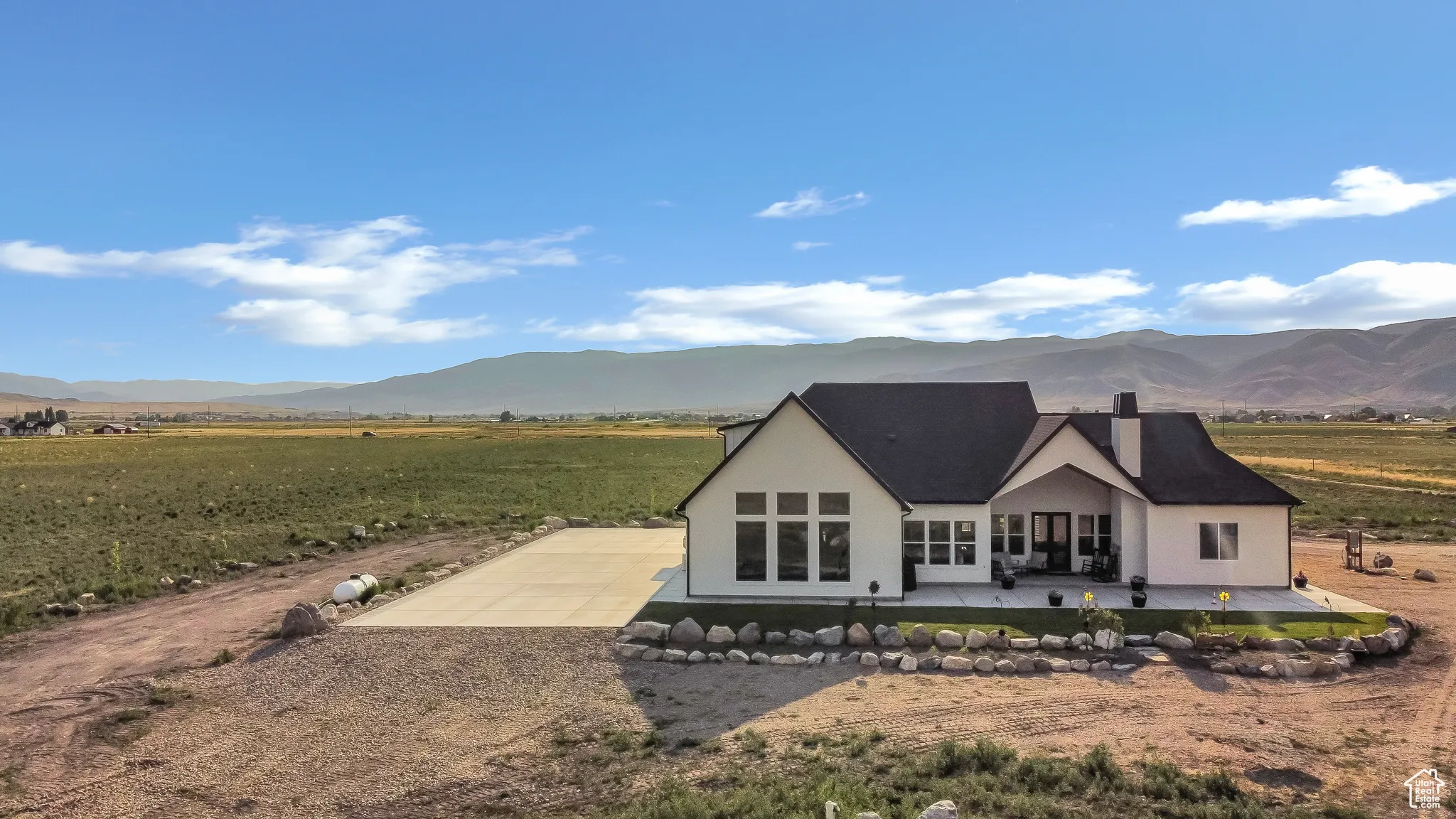 Back of house featuring a patio area, a mountain view, gravel driveway, and stucco siding