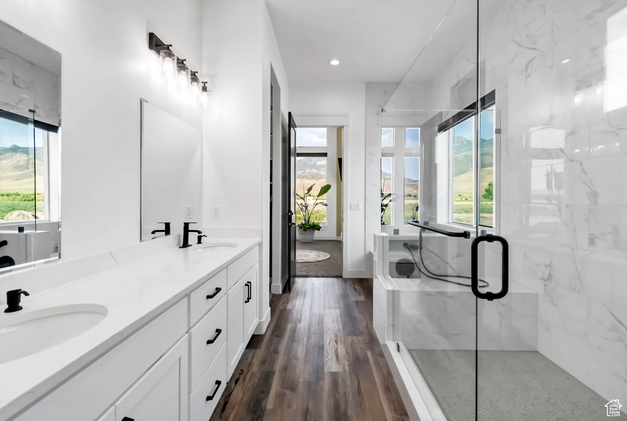 Bathroom featuring healthy amount of natural light, double vanity, a marble finish shower, and recessed lighting