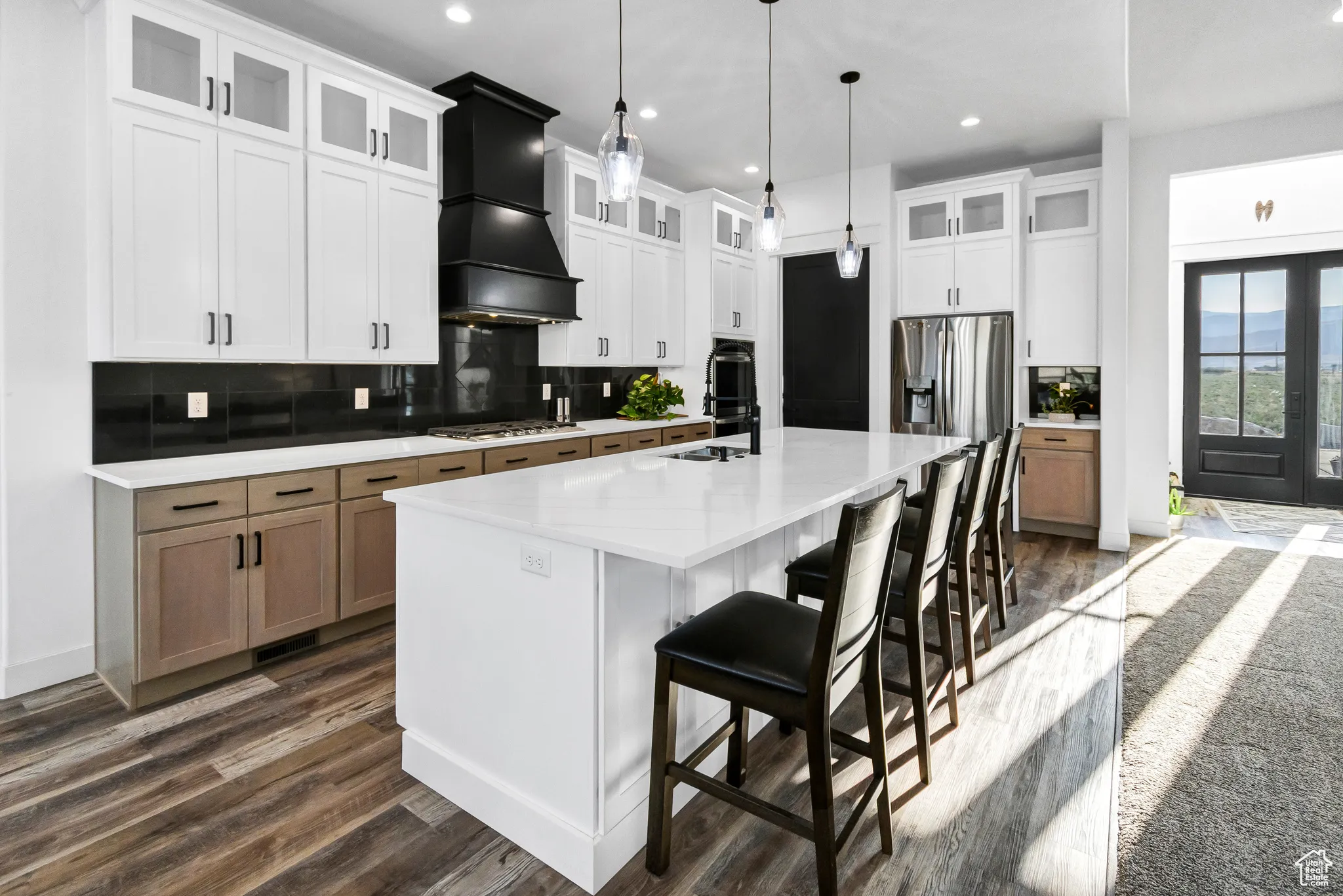 Kitchen with custom range hood, dark wood-style floors, a large island with sink, light countertops, and recessed lighting
