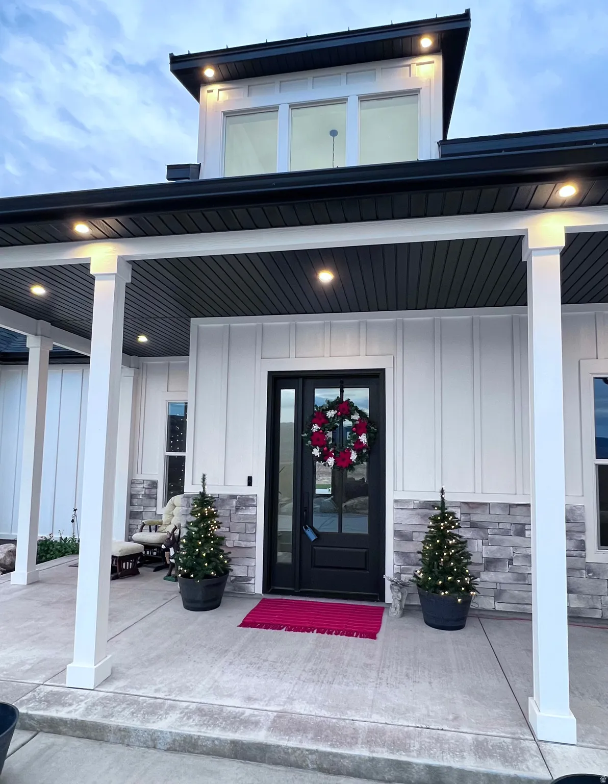 Property entrance with stone siding, covered porch, and board and batten siding