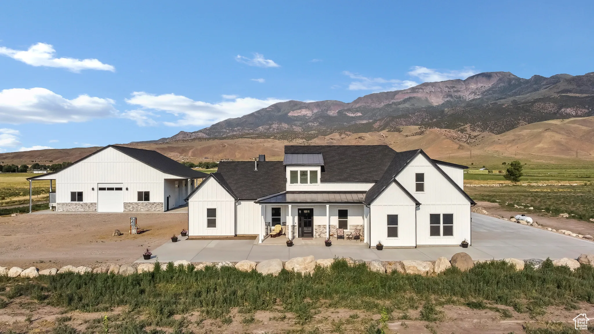 Rear view of property featuring a standing seam roof, a metal roof, a mountain view, and a patio