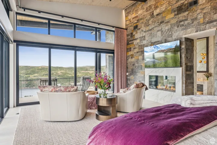 Bedroom with a high end fireplace, multiple windows, high vaulted ceiling, and wood ceiling