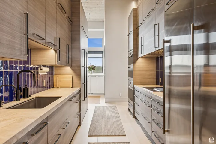 Kitchen with stainless steel built in fridge, tasteful backsplash, modern cabinets, and light countertops